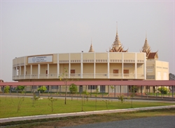 [ai] A circular, multi-story building with ornate spires on the roof, surrounded by a grassy area and a pathway. A sign on the front indicates the building's name, and the structure is positioned under a hazy sky.